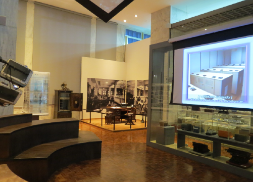 Foto de espa�o com pequena arquibancada e tel�o com reprodu��o de v�deo.